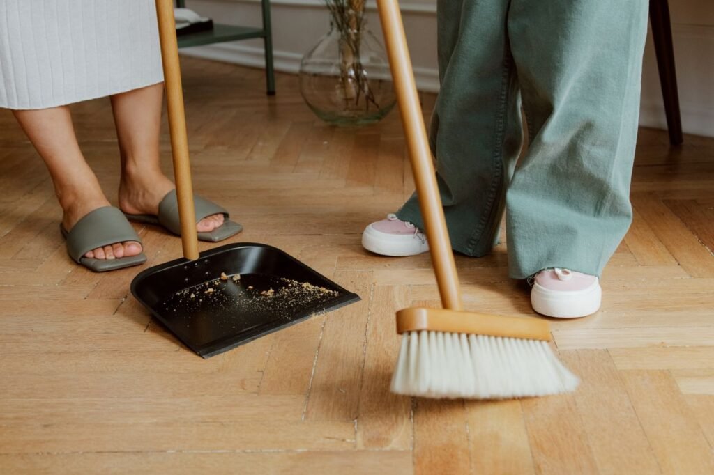 Mastering the First Impression: Your intriguing post title goes here Close-up of people cleaning wooden floor with broom and dustpan indoors.